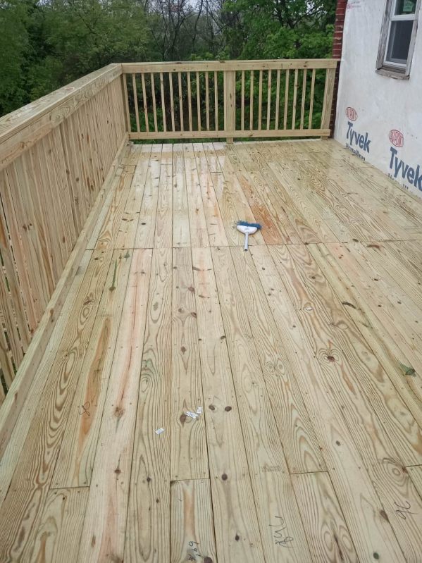 A newly built wood deck with a wood railing attached to the back of a house